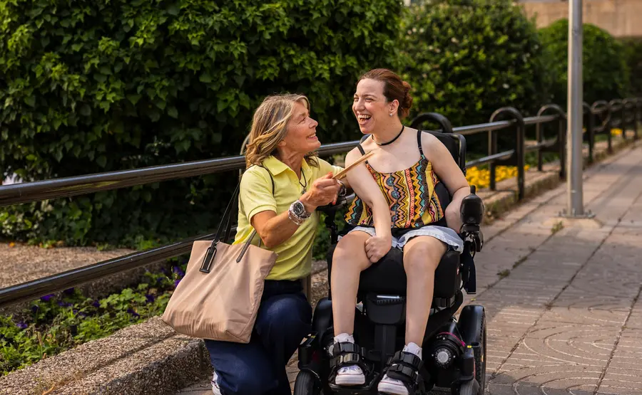 Young woman in a wheelchair and her female support worker having a conversation about coordination of care services